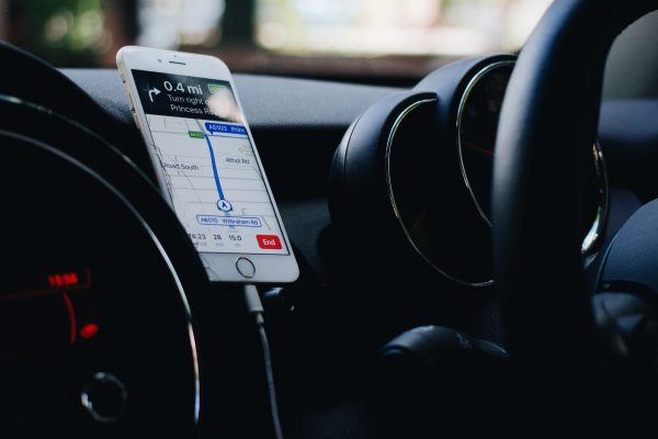 Ein Smartphone zeigt eine GPS-App geöffnet. Das Smartphone ist an einem Handyhalter in einem Fahrzeug befestigt.