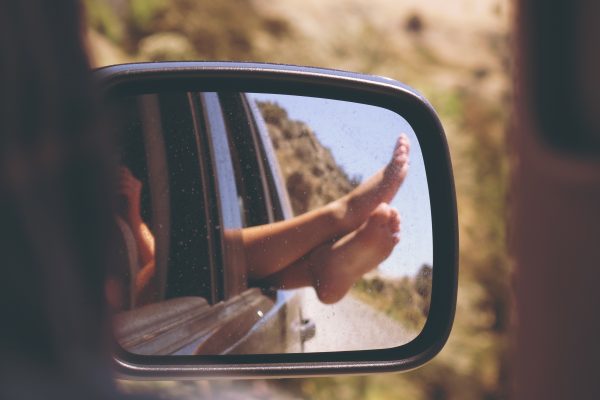 Ein Außenspiegel zeigt, dass eine Person die nackten Füße aus dem Fenster hängt.