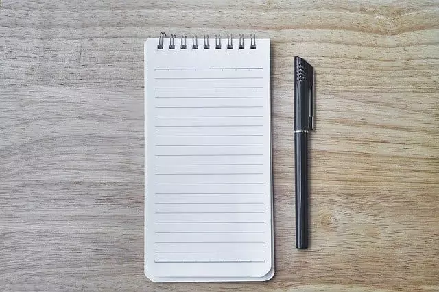 Stift liegt neben einem Notizblock.