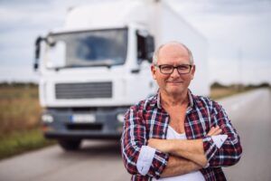 Mann steht lächelnd vor LKW