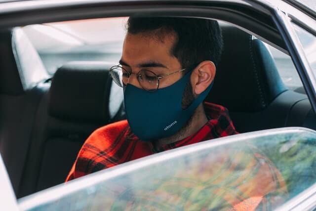 Person mit Maske im Auto