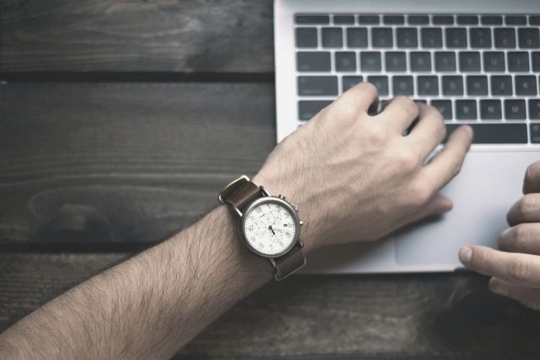 Ein Mann am Laptop mit Armbanduhr
